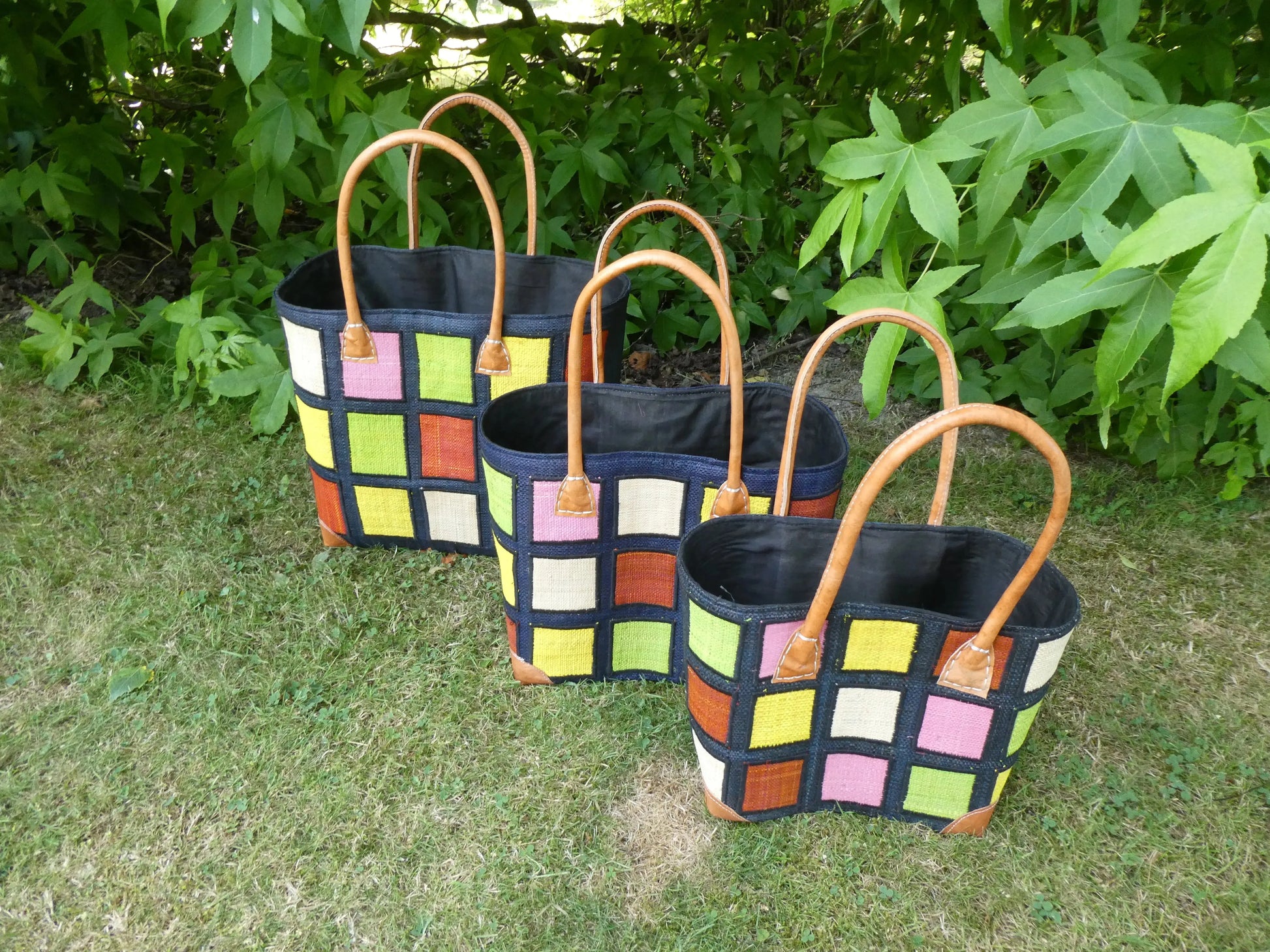 Cabas motif carré noir/blanc en cuir, panier artisanal trois tailles - photo de trois cabas colorés sur herbe